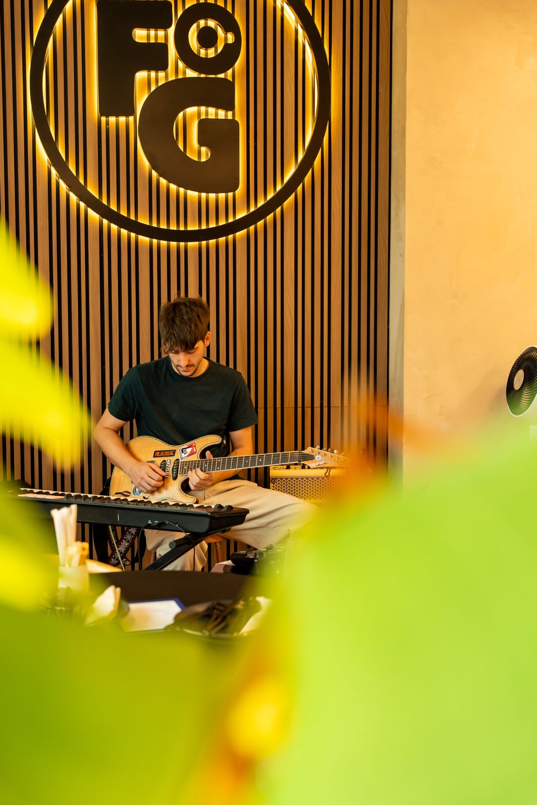 A guitarist playing live under the illuminated FG logo at Freshly Ground's Sunset Sessions