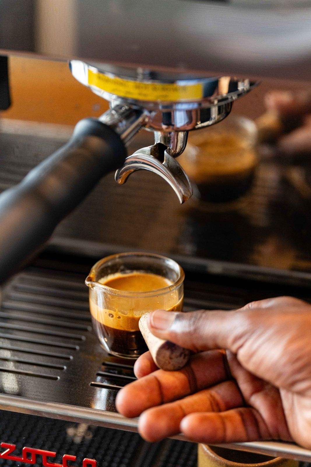 A fresh double espresso extracting from the machine into a glass at Freshly Ground