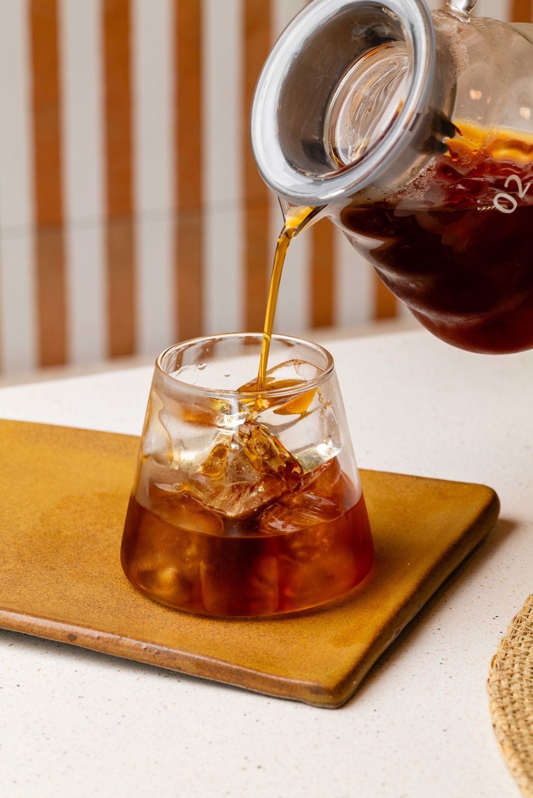 Iced filter coffee being poured from a glass carafe into a tumbler at Freshly Ground