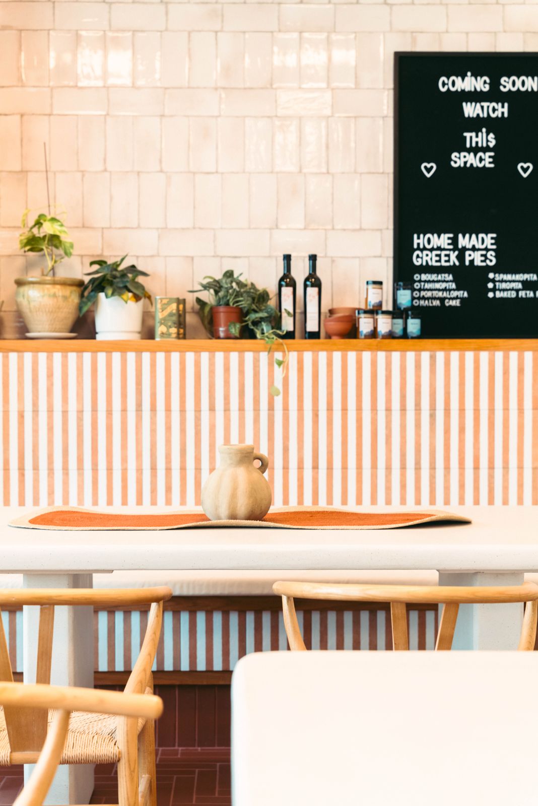 A Freshly Ground table with wishbone chairs and a chalkboard advertising homemade Greek pies
